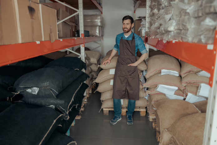 Productor observa sacos de café pergamino seco en bodega, con pantalla que muestra $2.285.000 la carga – 3 jul 2025